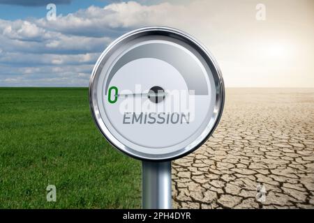 Gauge with inscription EMISSION and arrow points to zero on a background of landscape with half green field and half desert. High quality photo Stock Photo