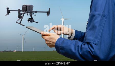 Engineer with tablet computer controls drone on a background of wind turbines. High quality photo Stock Photo