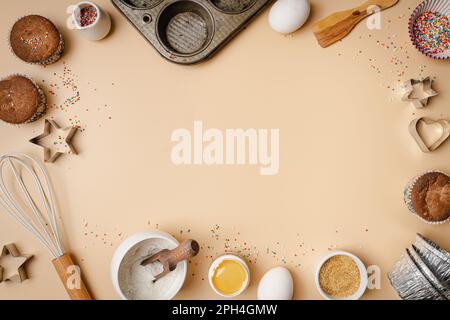 Baking or cooking colorful background. Ingredients, kitchen items for baking. Kitchen utensils, flour, eggs, sugar and muffins. Text space, top view. Stock Photo