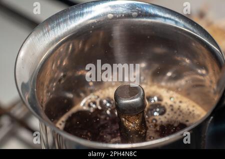 Freshly brewed coffee is poured through the nozzle of a geyser coffee maker and forms a foam, a large angle on top. Stock Photo