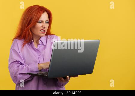 Mature redheaded woman having a problem with a laptop Stock Photo