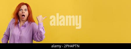 Amazed redheaded mature woman pointing surprised to the side Stock Photo