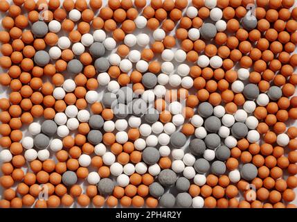 Many little balls of various sizes and colors create a pattern of white and gray colors on an orange background. Lots of spherical particles making an Stock Photo