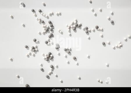 Many little white and gray balls scattered on a white background in the bright light, dropping shadows. Geometrical abstract futuristic wallpaper with Stock Photo