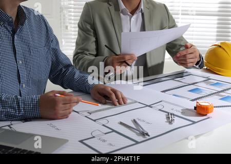 Architects working with construction drawings at table in office, closeup Stock Photo