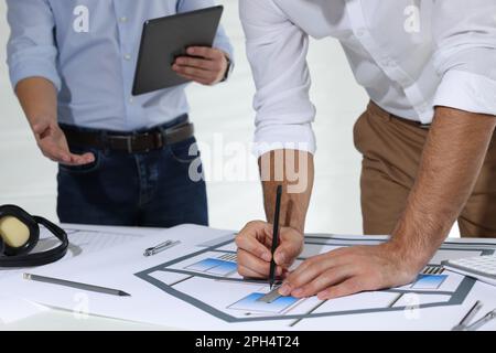 Architects working with construction drawings at table in office, closeup Stock Photo
