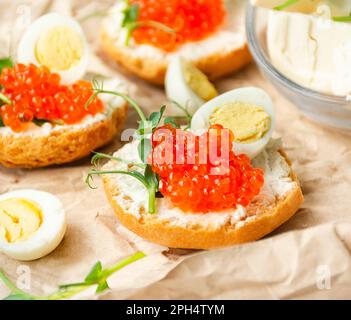 Canapes with red caviar are decorated with micro greens and quail eggs on paper. Close-up. Side view. Stock Photo
