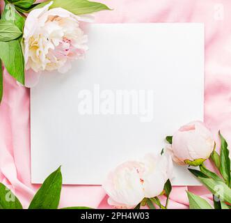 Frame of white and pink peonies on a pink fabric background. Flat lay. View from above. Copy space.Place for text. Stock Photo