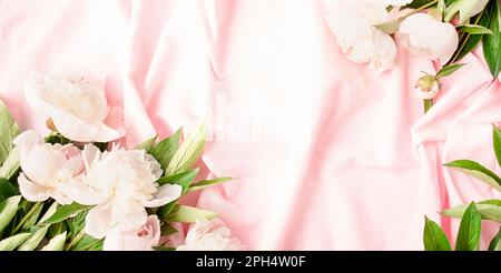 Frame of white and pink peonies on a pink fabric background. Flat lay. View from above. Copy space.Place for text. Stock Photo