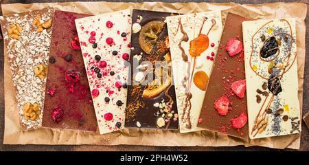 Handmade chocolate with berries, nuts, dried fruits on crumpled paper. Black and white chocolate. Chocolate bars. Close-up. Chocolate background. Culi Stock Photo
