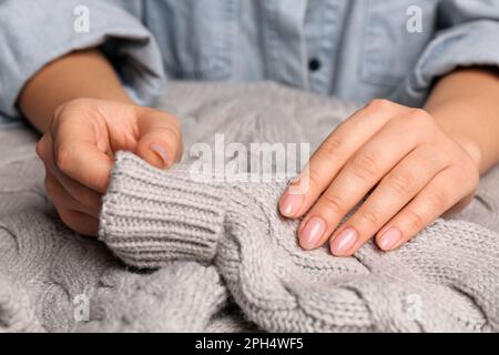 Woman touching soft grey knitted sweater, closeup Stock Photo