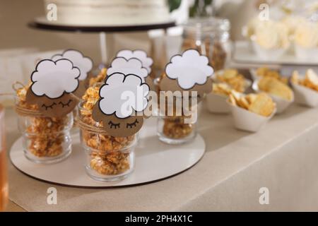 Tasty treats on table in room decorated for baby shower party Stock Photo