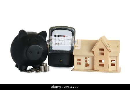 Electricity meter, house model, piggy bank and coins on white background Stock Photo