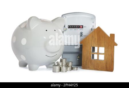 Electricity meter, house model, piggy bank and stacked coins on white background Stock Photo