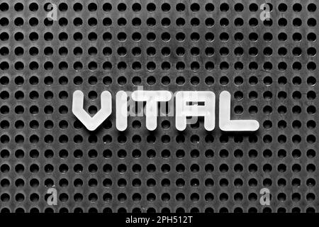 White alphabet letter in word vital on black pegboard background Stock Photo