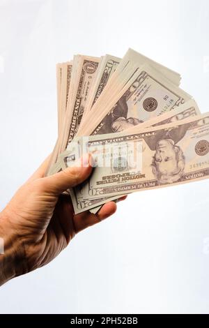 Man's hand holding a pile of dollars in the shape of a fan, on a white background. Stock Photo