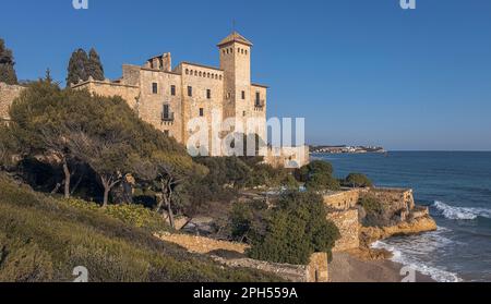 A picturesque beachfront castle, with towers and fortifications that harken back to a bygone era. The clear blue sky above highlights the stunning arc Stock Photo