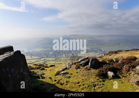 From high on Curbar Edge looking down in to a foggy Hope Valley with winter sunlight beginning to brighten the scene. Stock Photo