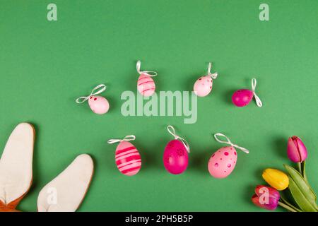 Easter eggs, bunny ears and tulips on green background Stock Photo