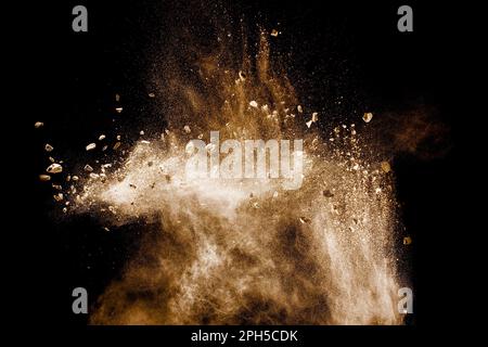 Split debris of stone exploding with brown powder against white background. Stock Photo
