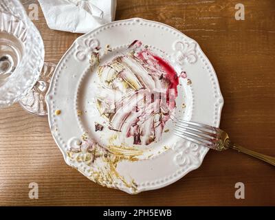 Dirty Plate After Eaten Dessert on the Wooden Table with Fork, Empty Glass and Used Napkin Stock Photo