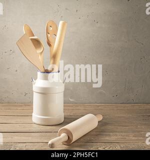 Wooden kitchen utensils. Various wooden tools in a clay vase on a table made of rough boards Stock Photo