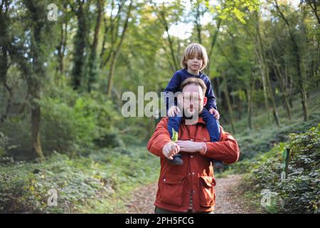 Father carrying son on his shoulders through the woods Stock Photo