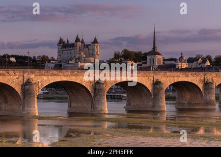 View over the Loire river during sunrise with the old bridge, the castle and the church of Saumur, France. Stock Photo