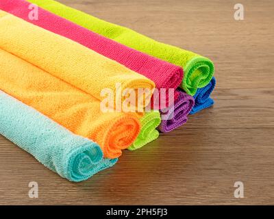 Stack of kitchen microfiber towels in bright colors on a brown wooden table Stock Photo