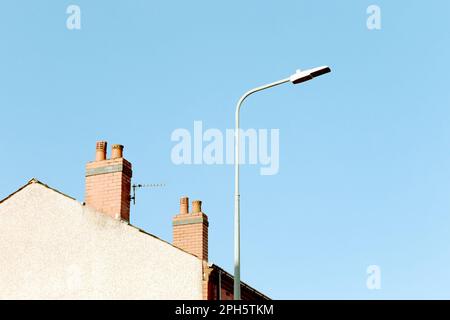 Street lamp post and two chimney pots on an end terrace house in a typical British street on a sunny morning with clear blue sky. Minimalist, abstract Stock Photo