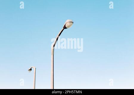 Street light lamp posts against pure blue cloudless sky. Minimalist photo, abstract. Blank canvas. Copy space for text, negative space, pastel colour Stock Photo