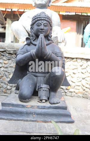 Statue of a god with snake around the neck in a setting position made up of rock. Stock Photo