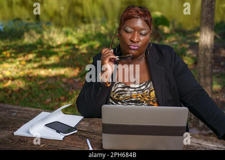 Businesswoman thinking with reading glasses by her face Stock Photo