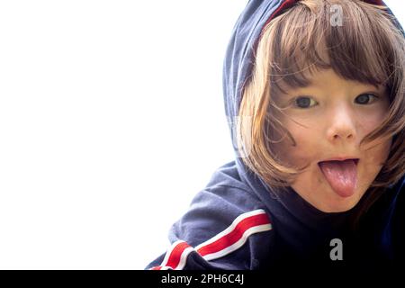 Defiant boy sticks tongue out in hoody Stock Photo