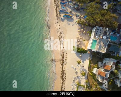 Elite resort complex on the seashore. Tall hotels, small bungalows, pools among palm trees. On the shore there are sun loungers, boats, beach umbrella Stock Photo