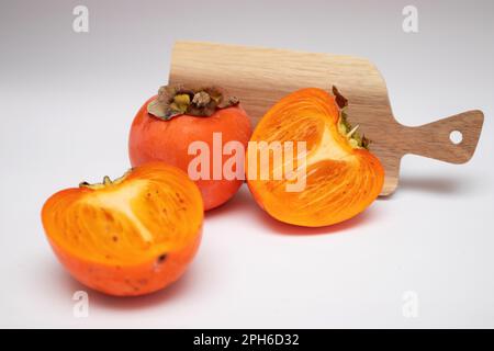Fresh persimmons and half of persimmons on white background Stock Photo
