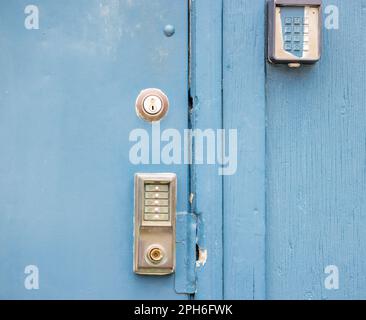 Closeup image of several different type of locks on an exterior blue metal door. Stock Photo