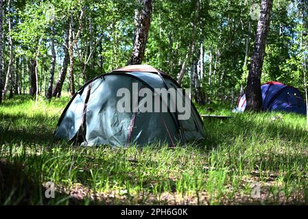 A girl sets up a camping tent during her stay in nature Stock Photo