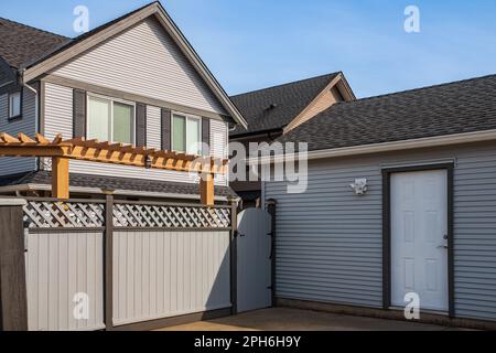 Modern detached storey house with gate grey fence in suburb street home. Wooden gate and fence on the back of the home. Street photo, nobody Stock Photo
