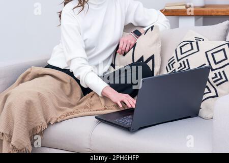 woman sitting on sofa indoor working with laptop Stock Photo