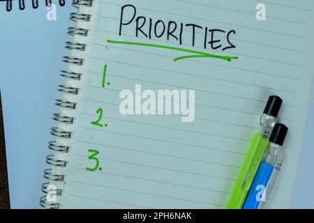 Concept of Priorities write on book. Supported by an additional services isolated on Wooden Table. Stock Photo