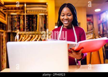 authentic ethnic africa america sellerwoman working in shop with laptop Stock Photo