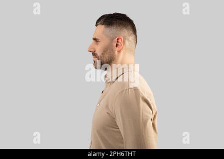 Profile portrait of bearded middle aged man in shirt, standing on light grey studio background, side view, free space Stock Photo