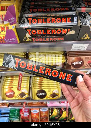 25.03.2023 Ukraine, Kharkov Chocolate Toblerone in hand. Delicious chocolate on store shelves. Swiss dark chocolate with honey almond nougat  Stock Photo