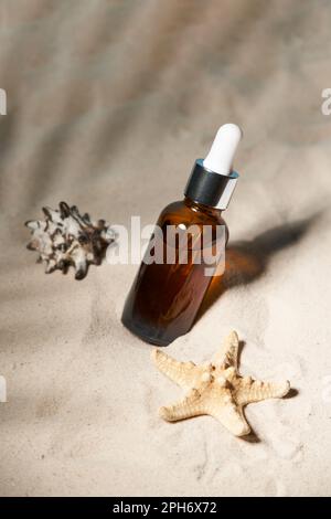 Summer sunscreen essence on sand background with seashells and starfish. Beach holiday cosmetics. Stock Photo