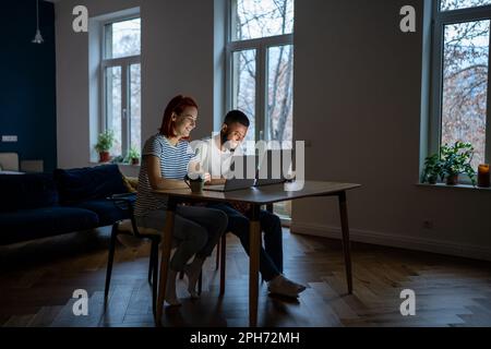 Young diverse couple running small online business at home, man and woman working on laptops Stock Photo