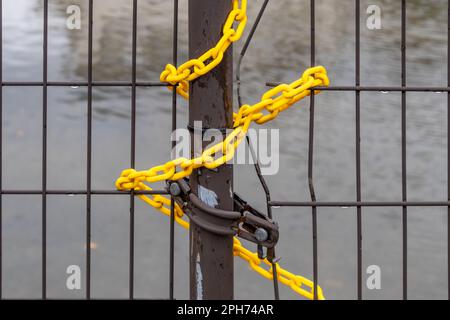 Yellow plastic chain on metal gate, with water in background, Kanazawa, Japan. Stock Photo