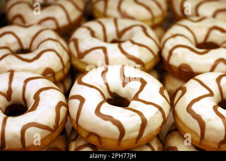 Doughnuts in white glaze close up. Sweet donuts in a store, high calorie food Stock Photo