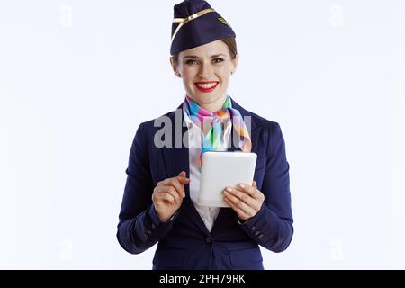 happy modern air hostess woman against white background in uniform using tablet PC. Stock Photo