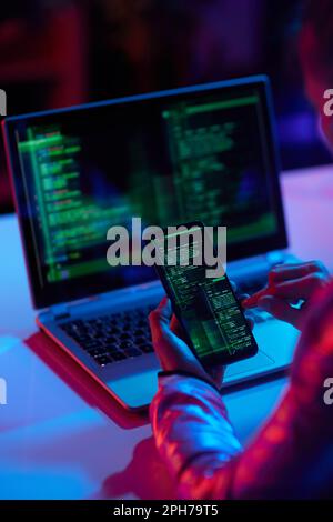 Seen from behind modern business woman with laptop and smartphone protecting network against cyberattack from hackers on internet in modern office. Stock Photo